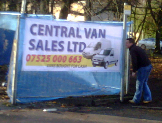 banner on fence advertising a used van dealers