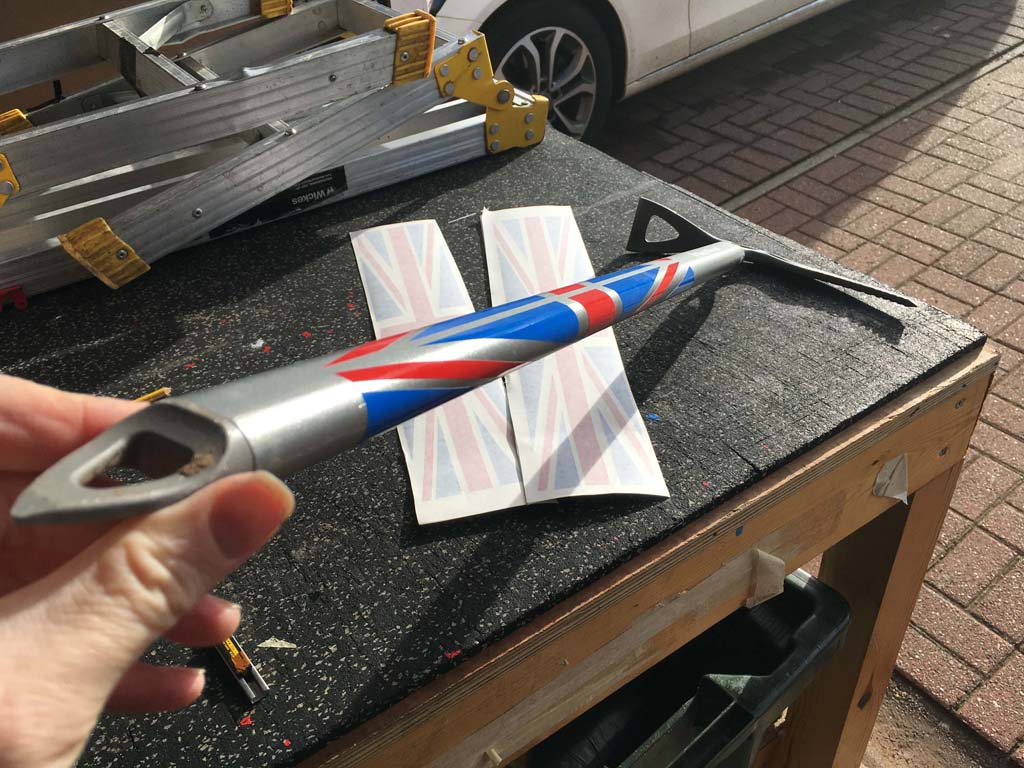 Image of climbers axe with union jack style decals applied round handle with extra set of decals underneath axe on worktop