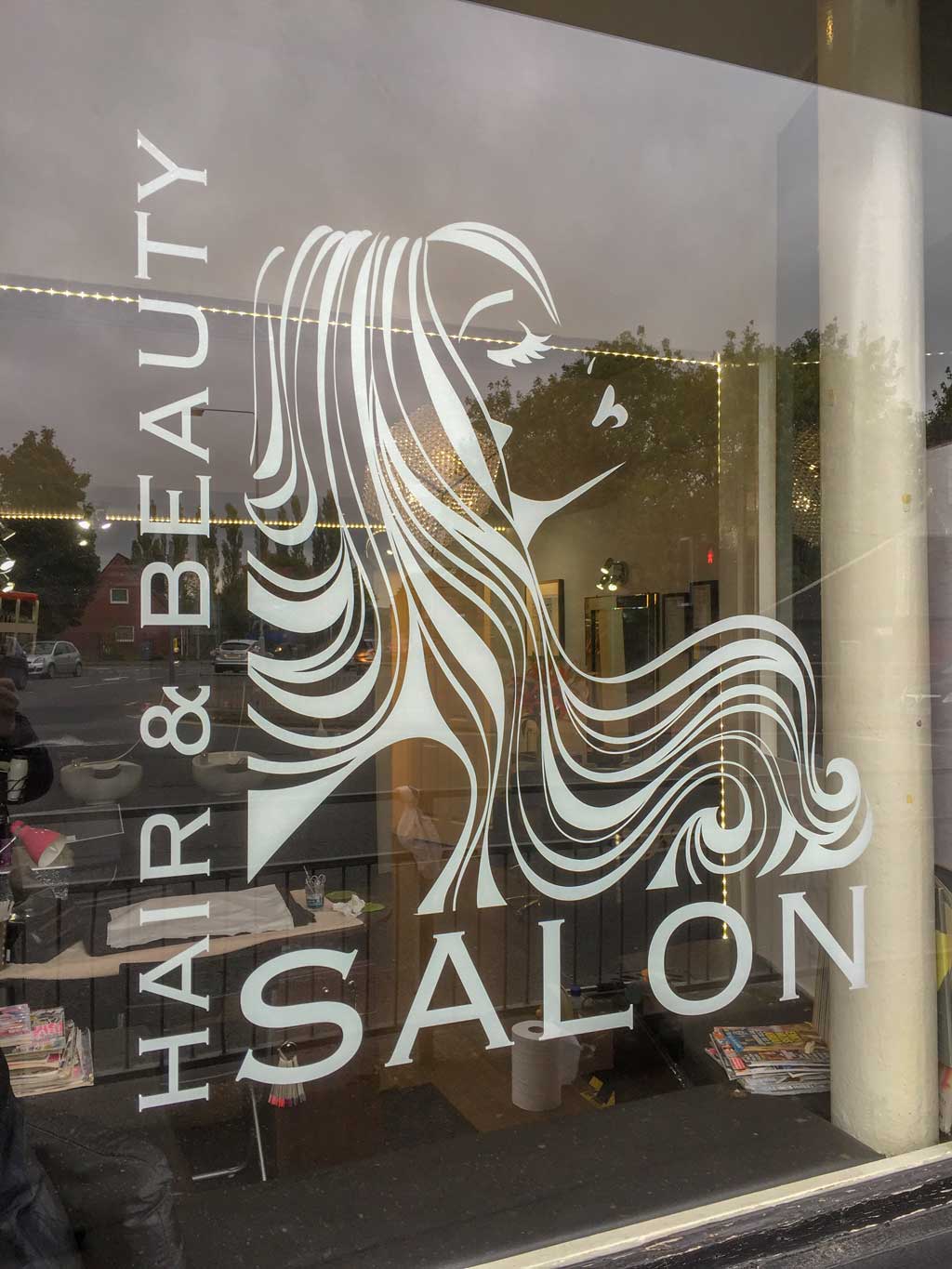 white vinyl graphic on window of gorgeous ladies head profile with flowing hair and text saying hair and beauty salon